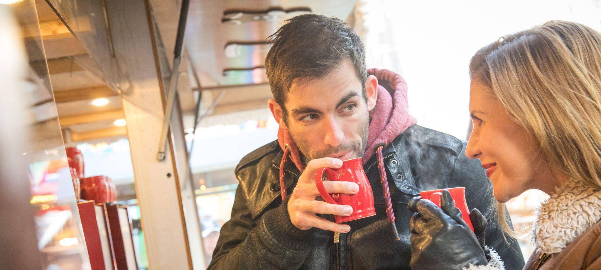 Ein Mann und eine Frau trinken Heißgetränk auf Weihnachtsmarkt