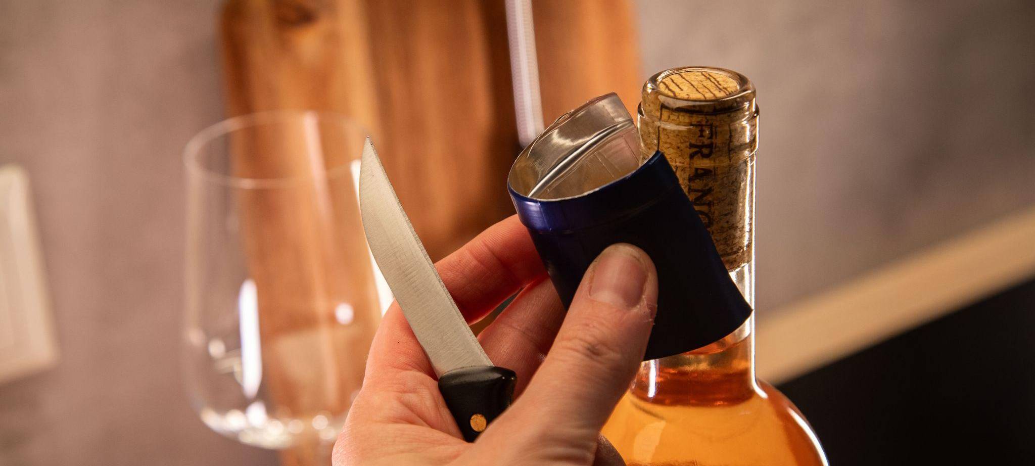 Banderole wird vom Flaschenhals eines Weins entfernt