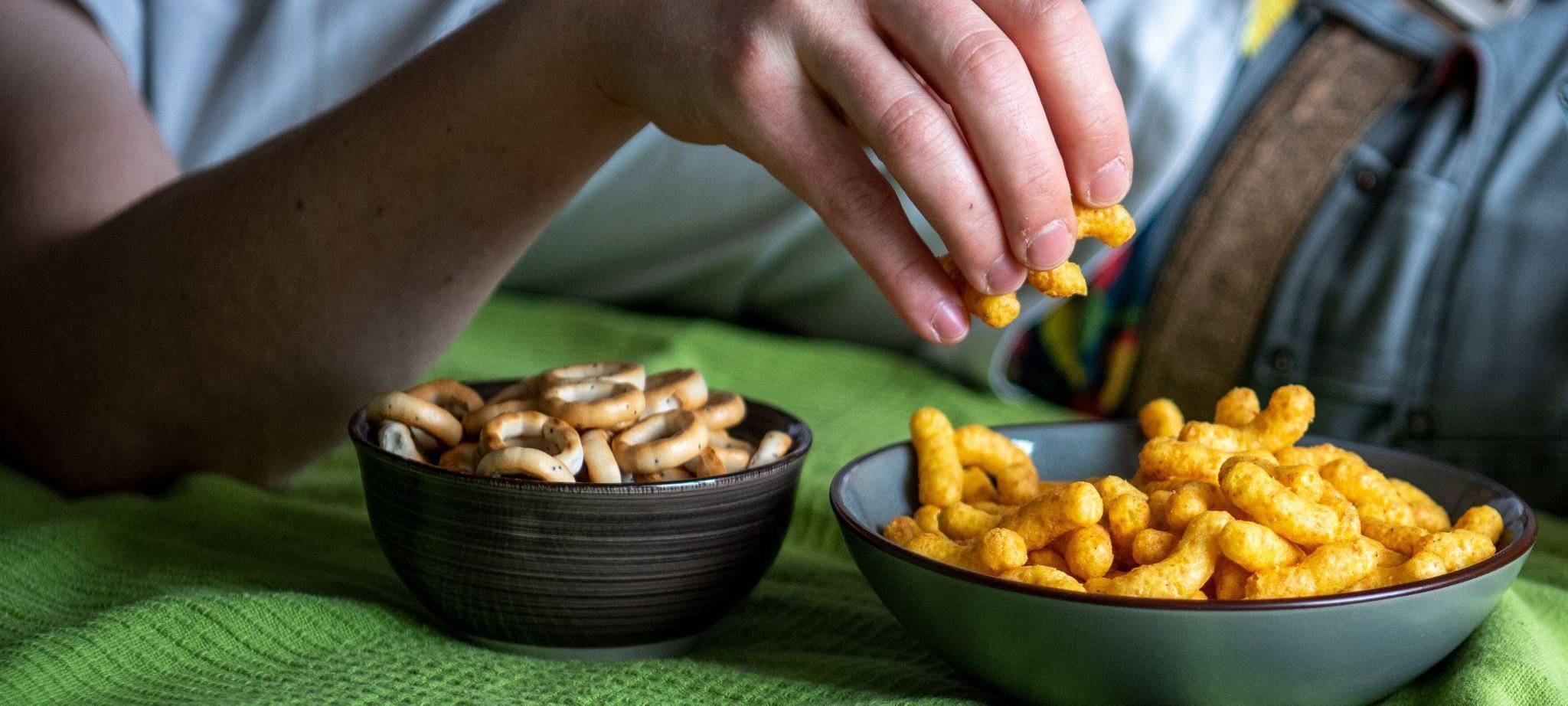 Mann isst auf einem Sofa Chips