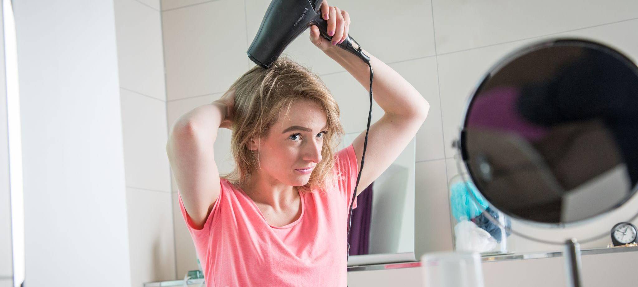 Eine junge Frau föhnt ihre Haare